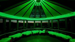 A room with a green-lit dome ceiling, large windows, and plush green seating. - Klettar Tower Iceland (Selfoss)