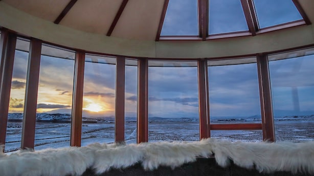 A room with a large window overlooking a snowy landscape at sunset. - Klettar Tower Iceland (Selfoss)
