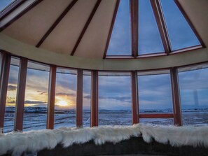 A room with a large window overlooking a snowy landscape at sunset. - Klettar Tower Iceland (Selfoss)