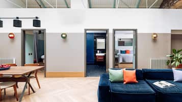 A modern interior with a dining area, a blue sofa, and a kitchen visible through an open door.