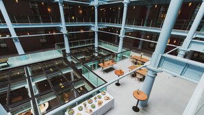 A multi-level atrium with glass railings, tables, and seating areas. - Native Manchester (Manchester)