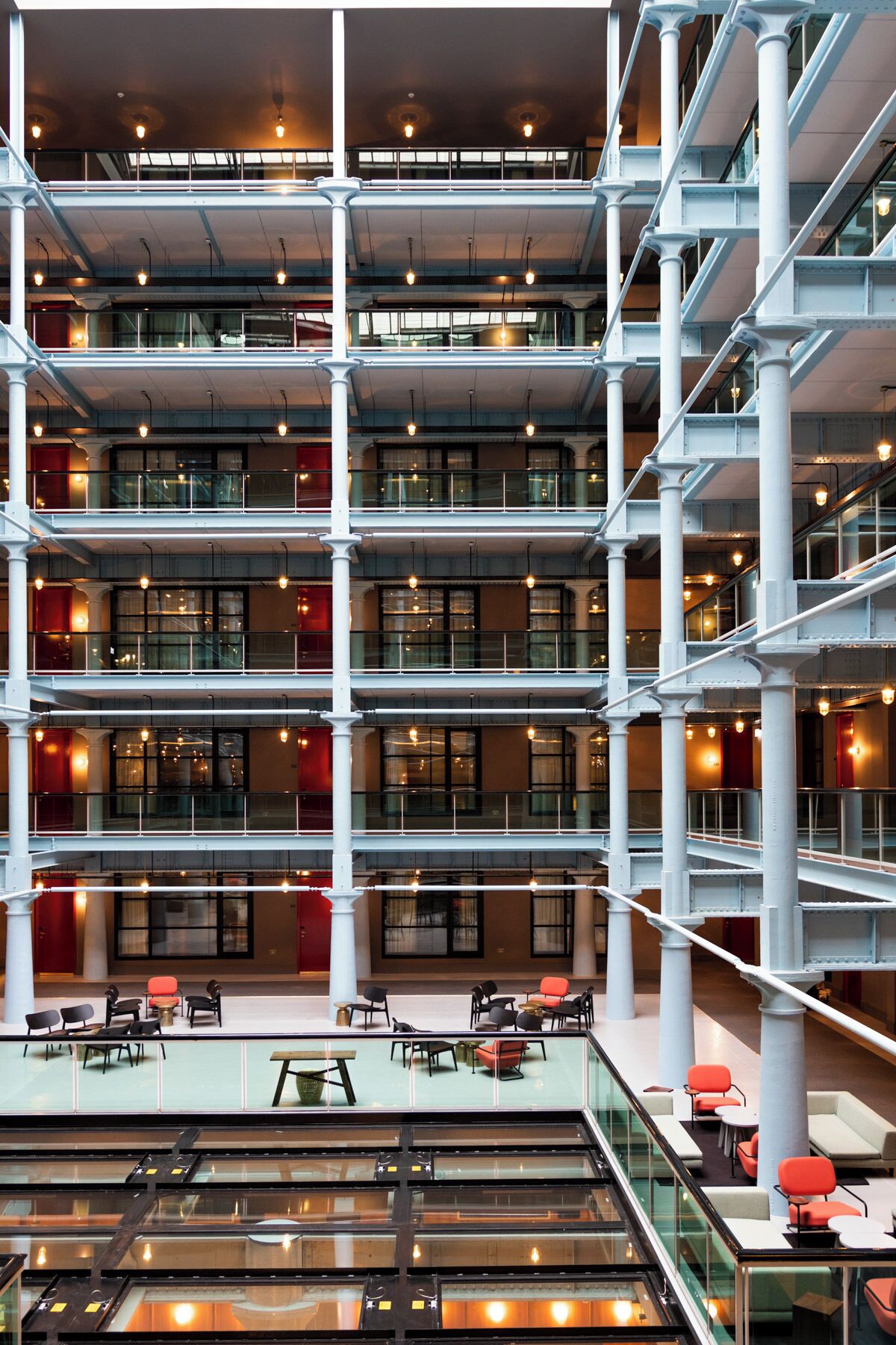 Un atrium à plusieurs niveaux, doté de rampes en verre, de nombreux étages et d’espaces aménagés pour s’asseoir.