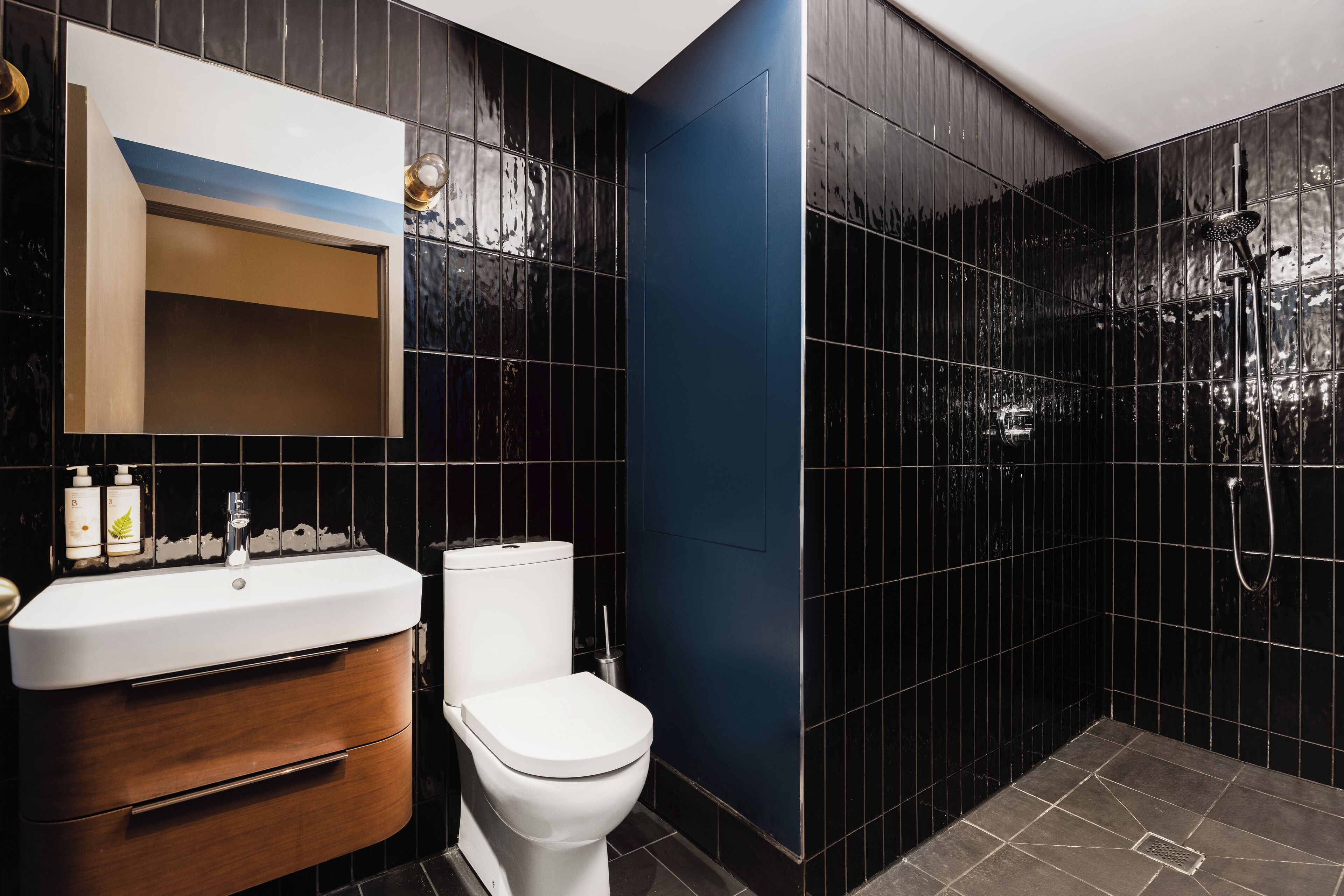 A modern bathroom with a white sink, wooden vanity, and a toilet.