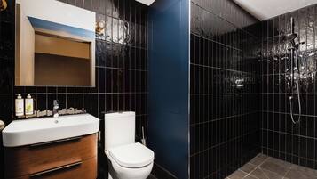 A modern bathroom with a white sink, wooden vanity, and a toilet.