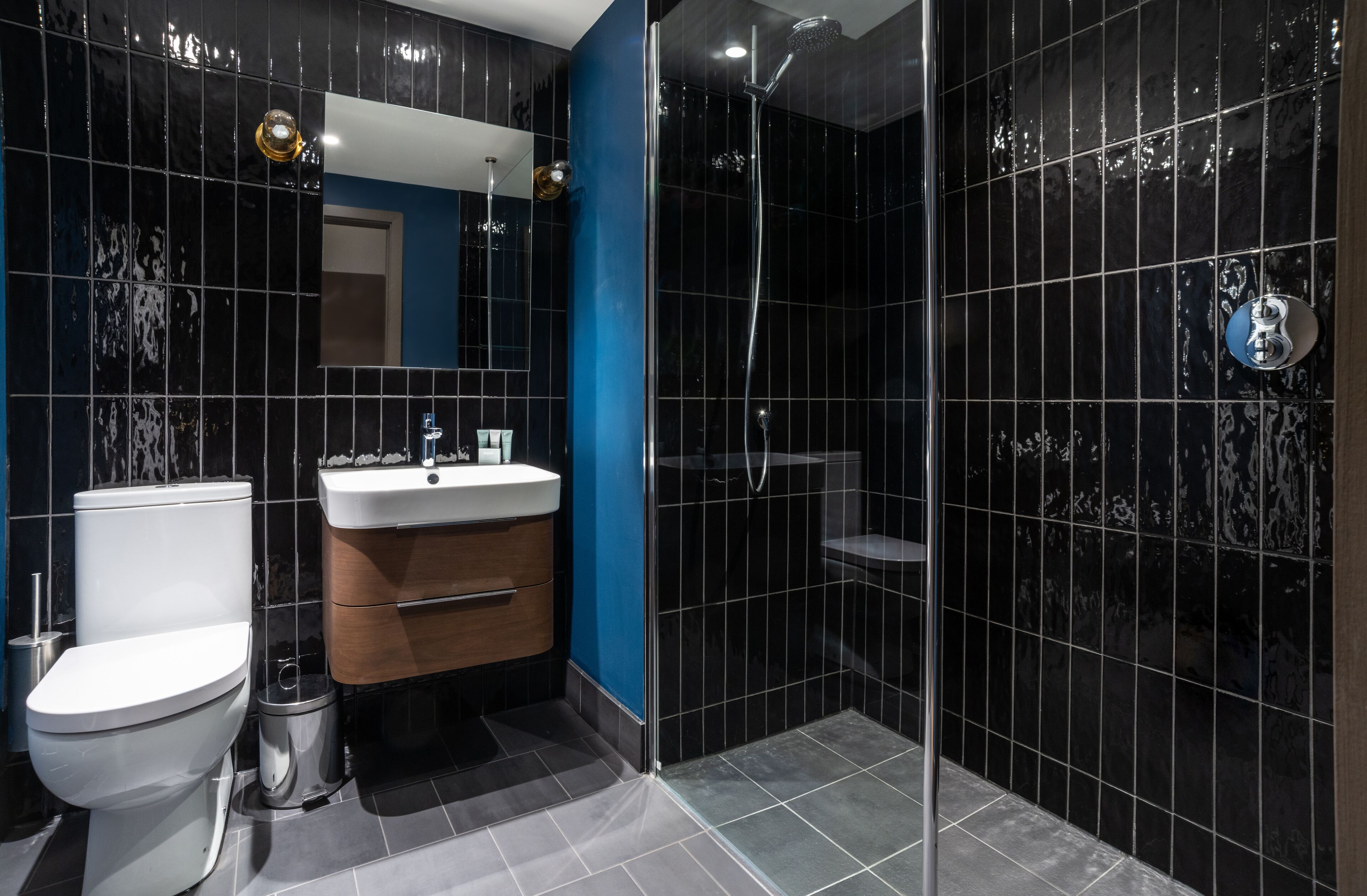 A modern bathroom with a toilet, sink, vanity, and a glass-enclosed shower area.