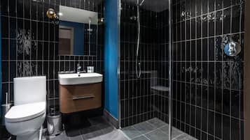 Un baño moderno con inodoro, lavabo, tocador y zona de ducha con mampara de vidrio.