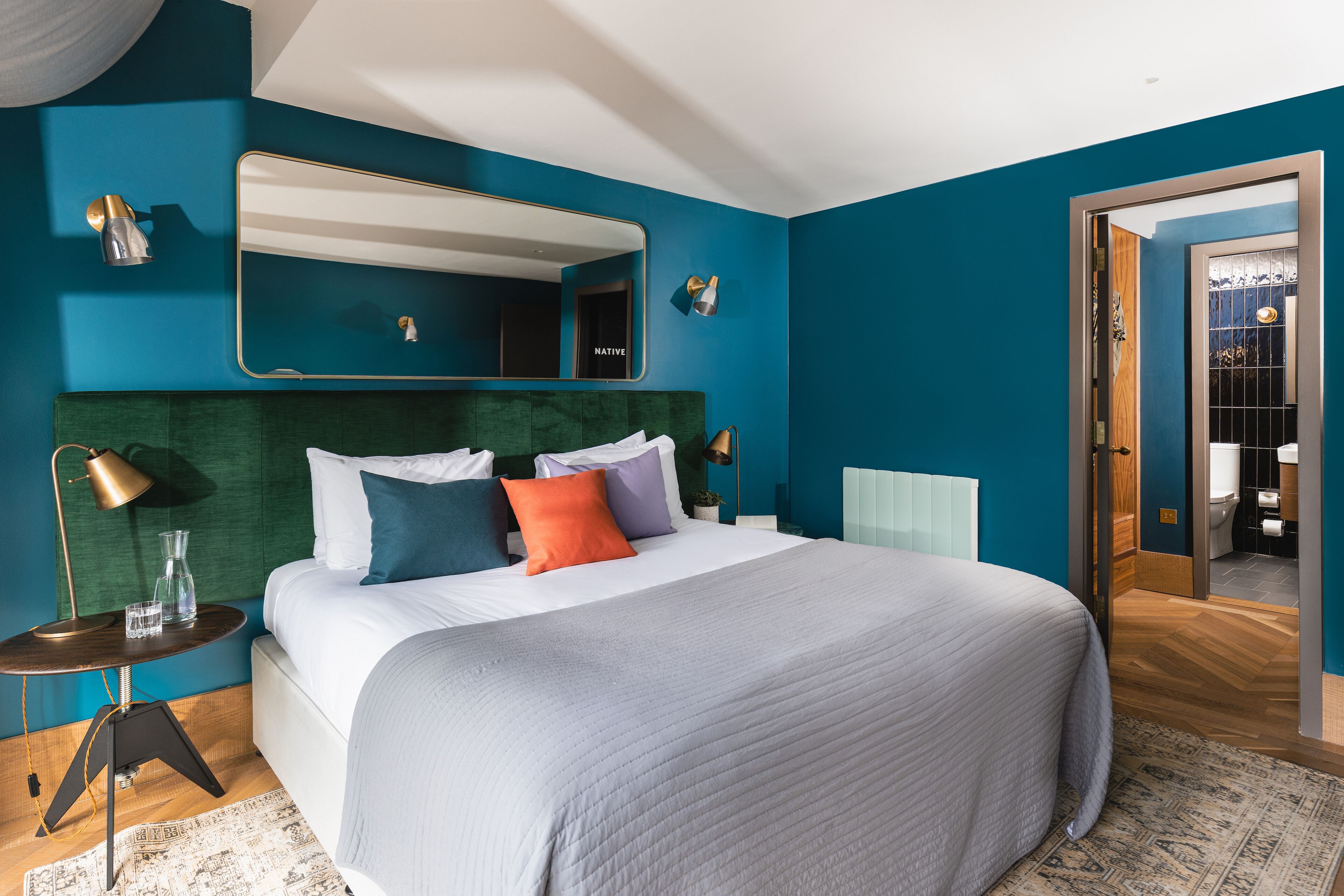 Une chambre avec un grand lit, un miroir, des lampes de chevet et une vue sur la salle de bain.