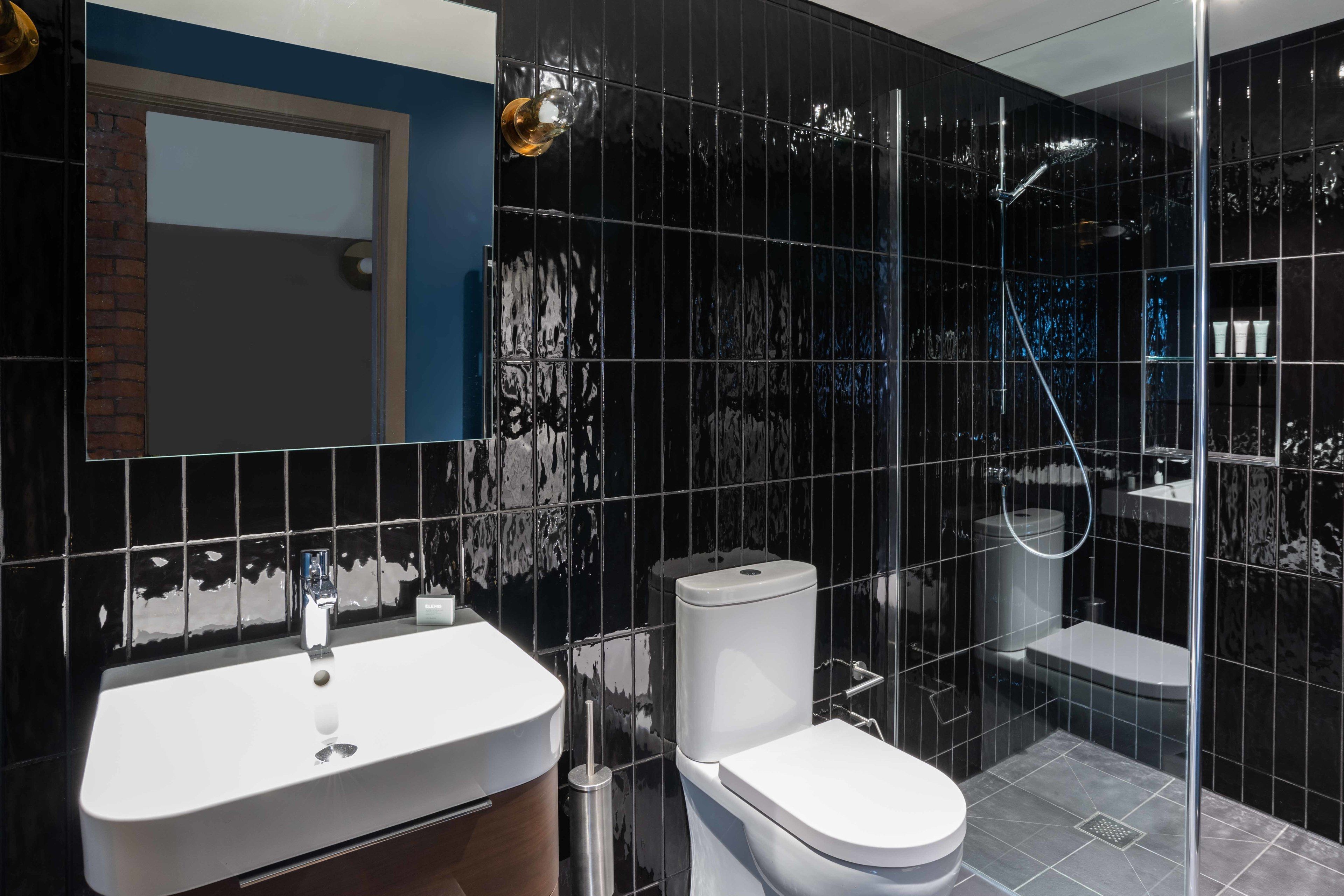 A modern bathroom with a white sink, toilet, and shower enclosure.