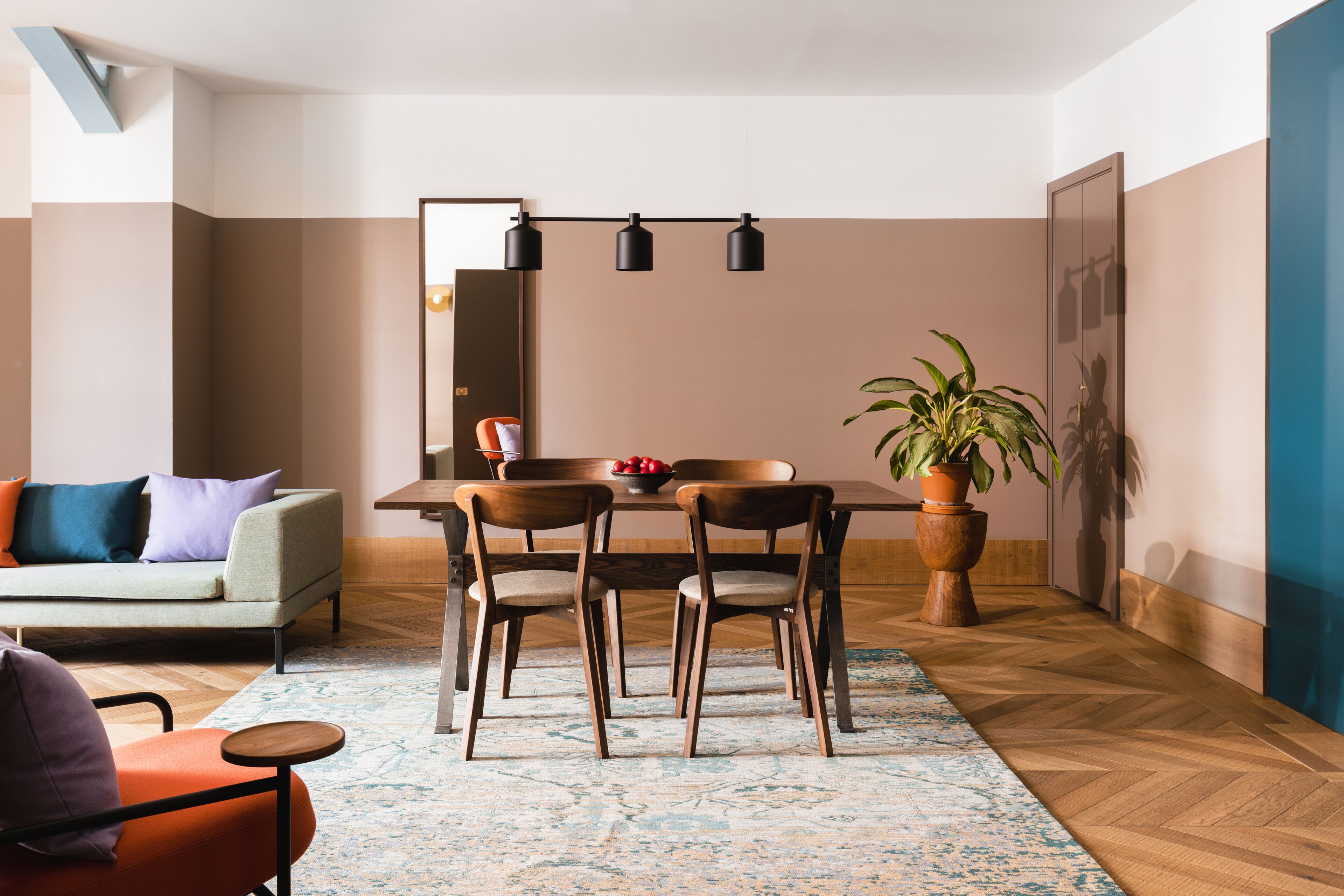 A modern dining area with a wooden table, four chairs, and a potted plant.