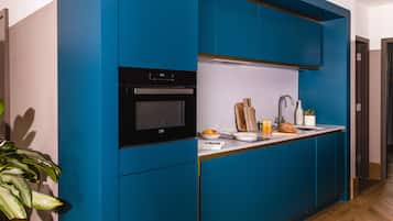 Una cocina moderna con armarios azules, un horno integrado y una encimera con un lavabo y varios utensilios de cocina.