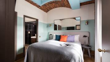 A hotel room with a large bed, a bedside table, a mirror, and a door.