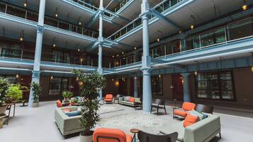 A spacious indoor area with multiple levels, featuring seating arrangements and potted plants.