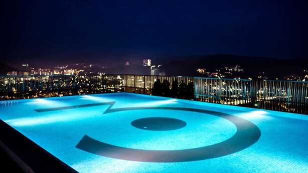 Ein Pool auf dem Dach mit Blick auf die nächtliche Stadtlandschaft.