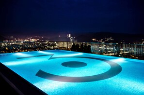 En pool på taket med utsikt över staden, särskilt vacker på kvällen.