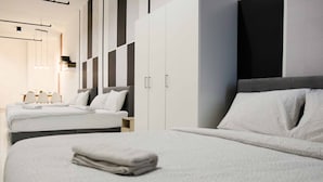 Ein modernes Hotelzimmer mit zwei Betten, einem großen Kleiderschrank und einem Essbereich mit Tisch und Stühlen.