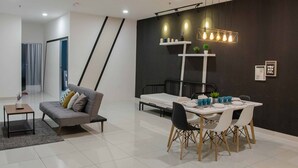 Ein modernes Wohnzimmer mit einem grauen Sofa, einem Esstisch mit Stühlen und einer Wand mit schwarz-weißen Streifen.