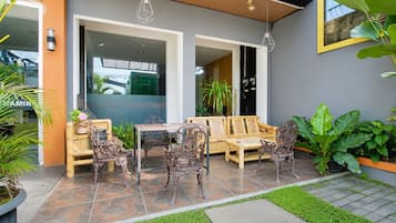 Un área de estar al aire libre con una mesa y sillas, rodeada de plantas en macetas y un patio con baldosas de piedra.