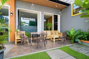 Un área de estar al aire libre con una mesa y sillas, rodeada de plantas en macetas y un patio con baldosas de piedra.