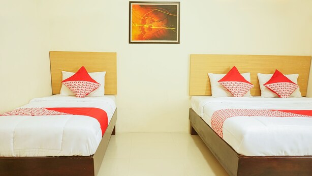 Two identical twin beds with wooden headboards, white bedding, and red patterned pillows.