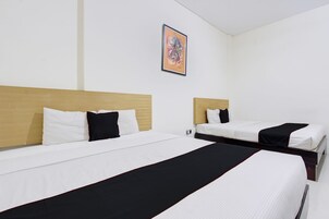 Habitación de hotel con dos camas, cada una con ropa de cama blanca y detalles negros, cabeceros de madera y un cuadro en la pared.