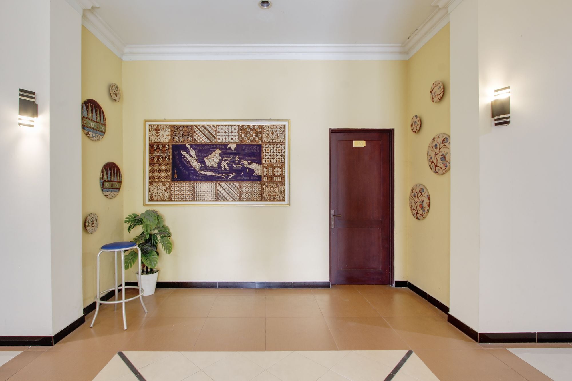A hallway with a large decorative wall piece, a potted plant, and a door.