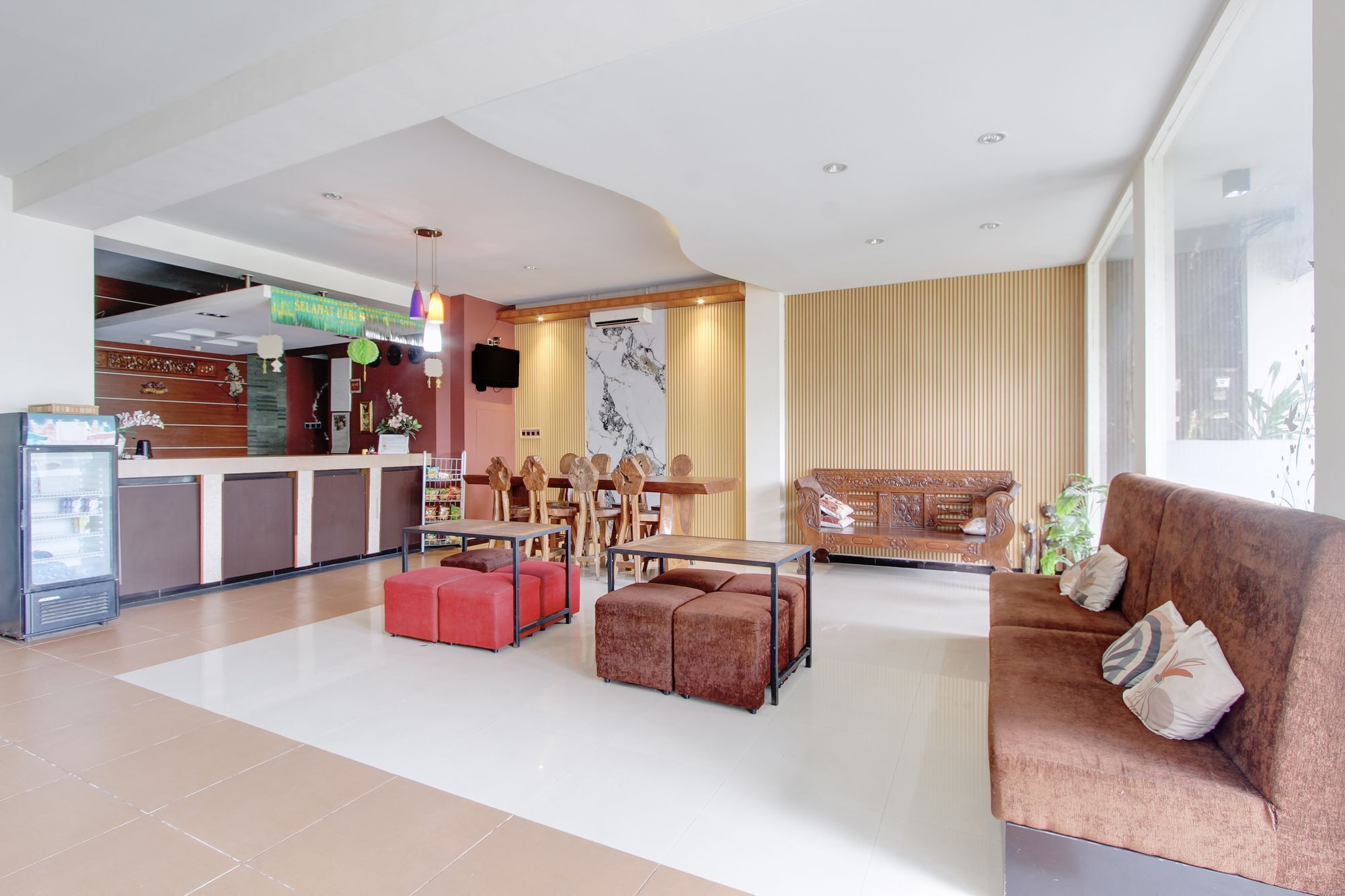Een hotel lobby met een receptiebalie, een zithoek en een groot raam.