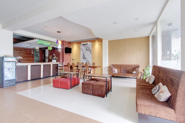 A hotel lobby with a reception desk, seating area, and a large window.