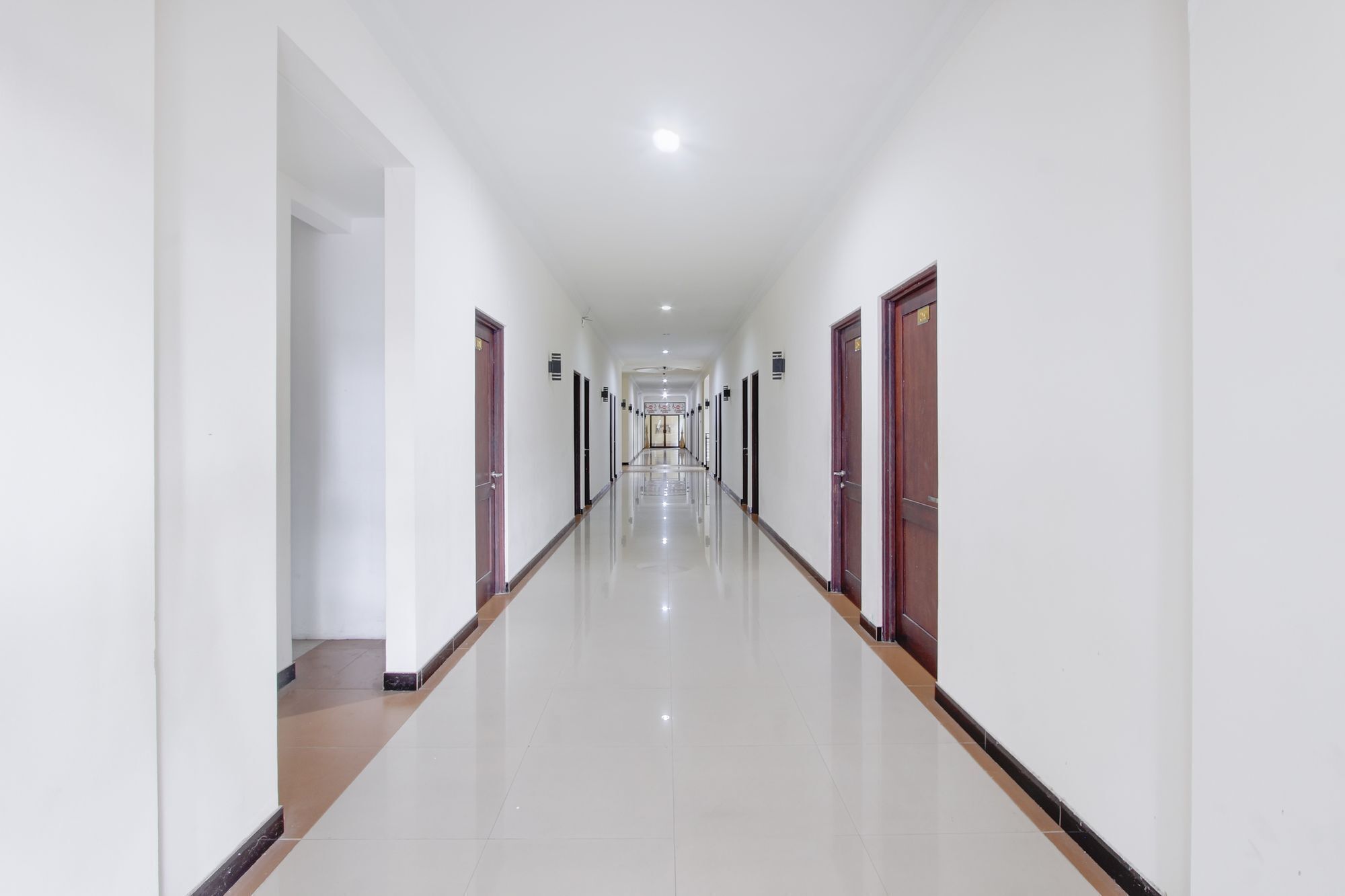 A long, narrow hallway with doors on both sides, leading to rooms.