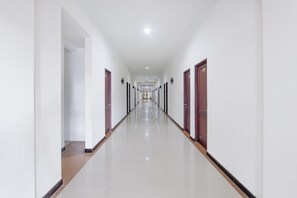 A long, narrow hallway with doors on both sides, leading to rooms. - Hotel O near Jogja City Mall formerly Namira Hotel (Pogung Lor)