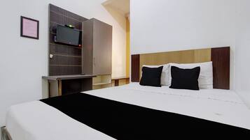 Habitación de hotel con cama, televisor montado en la pared y armario de madera.