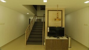 Un escalier menant à un palier où se trouve un téléviseur à écran plat et, en dessous, un petit meuble.