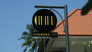 Une enseigne pour l’hôtel Chandra Inn, avec un logo circulaire et le nom de l’établissement.