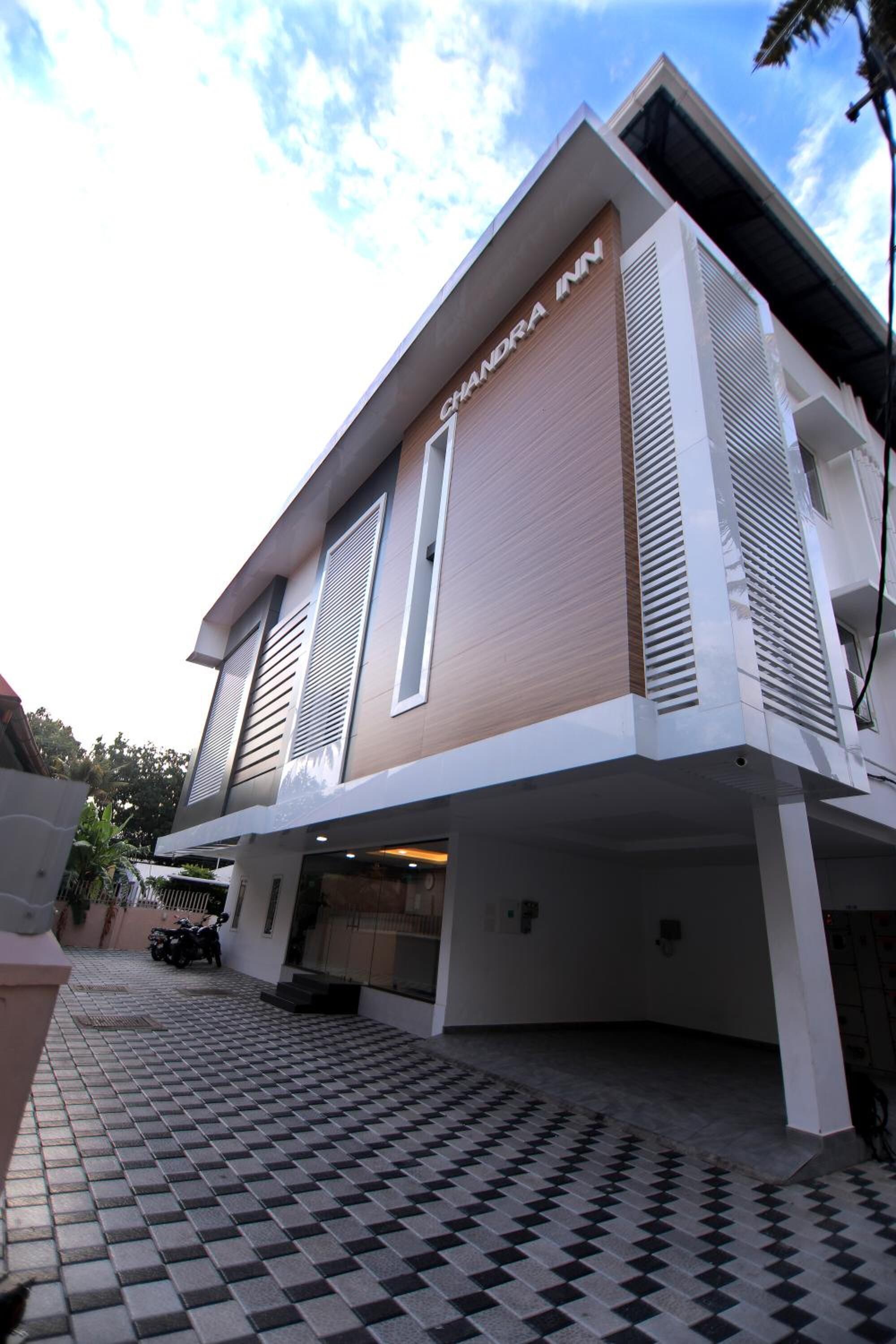 A modern hotel with a flat roof, large windows, and a checkered tile entrance.