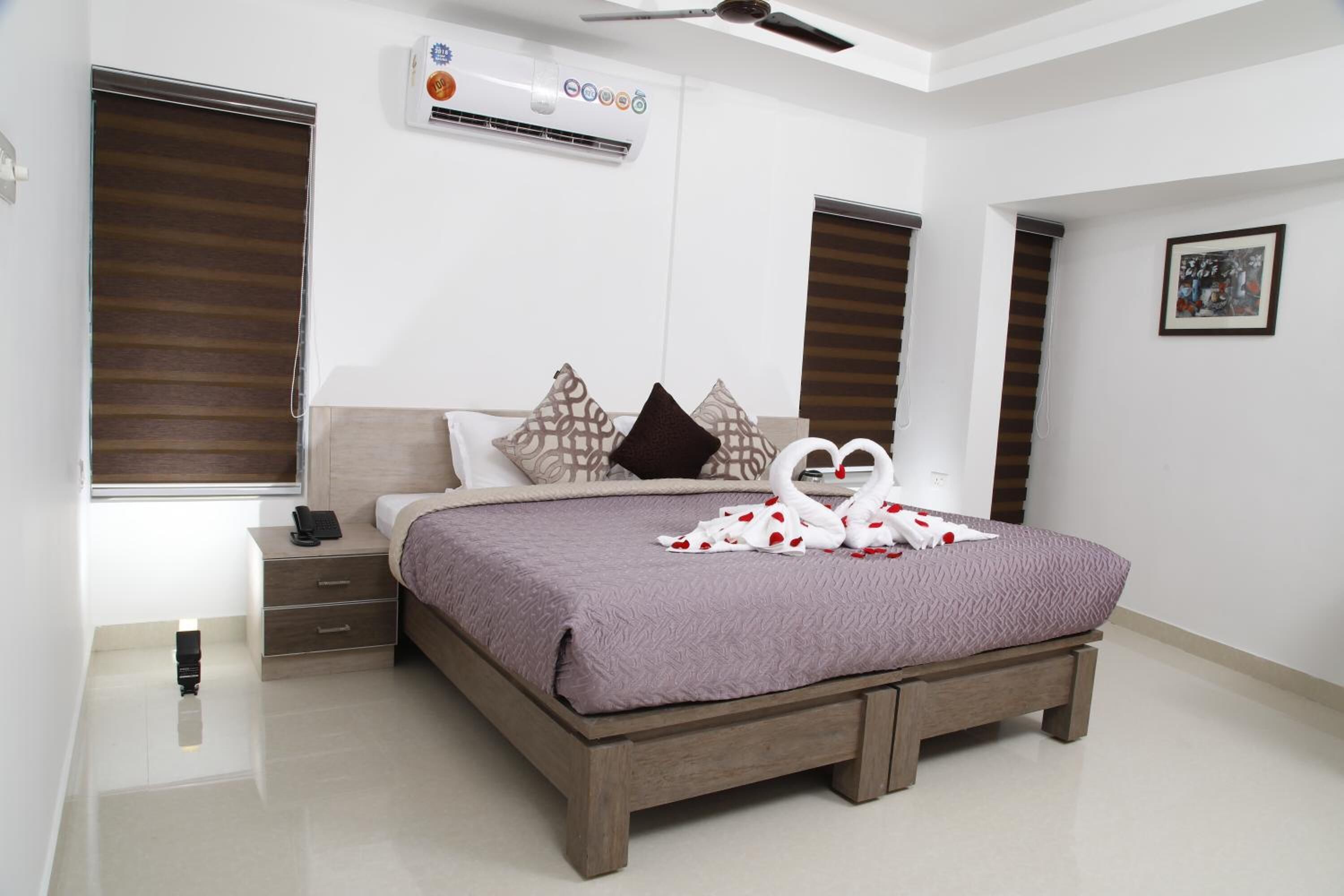 A modern bedroom with a large bed, a bedside table, a nightstand, and a wall-mounted air conditioner.
