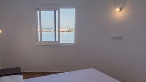 Ein Schlafzimmer mit großem Fenster, einem Bett und einer Wandleuchte.
