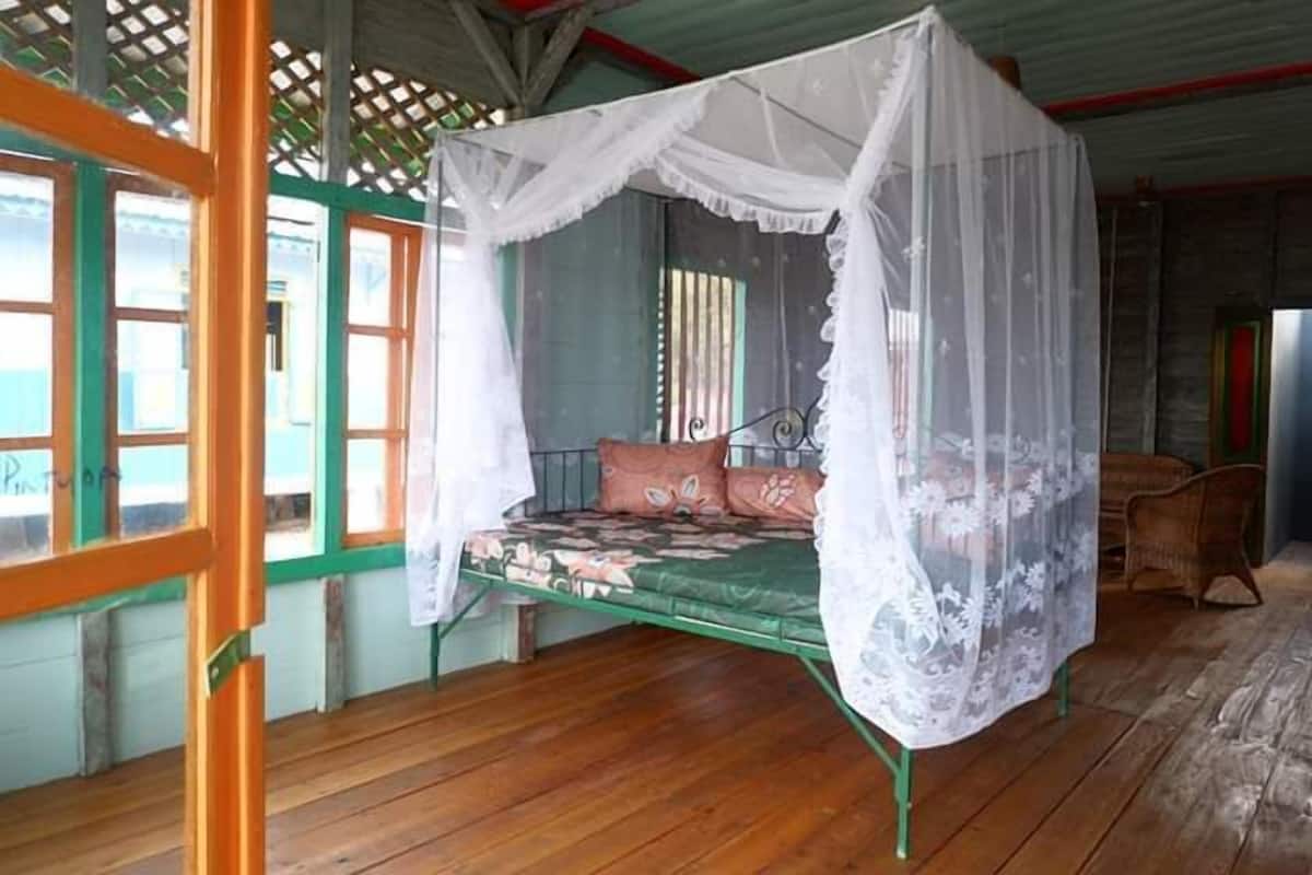 Ein Zimmer mit einem Bett unter einem Baldachin, einem Fenster mit Blick und einem Sessel.