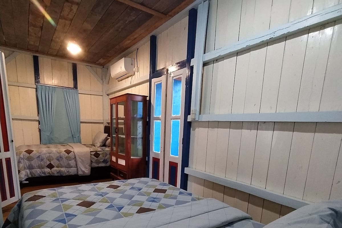 Ein Schlafzimmer mit zwei Betten, einem Holzschrank und einem Fenster mit Vorhängen.