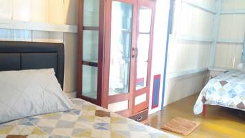A room with two beds, a wardrobe, and a window.
