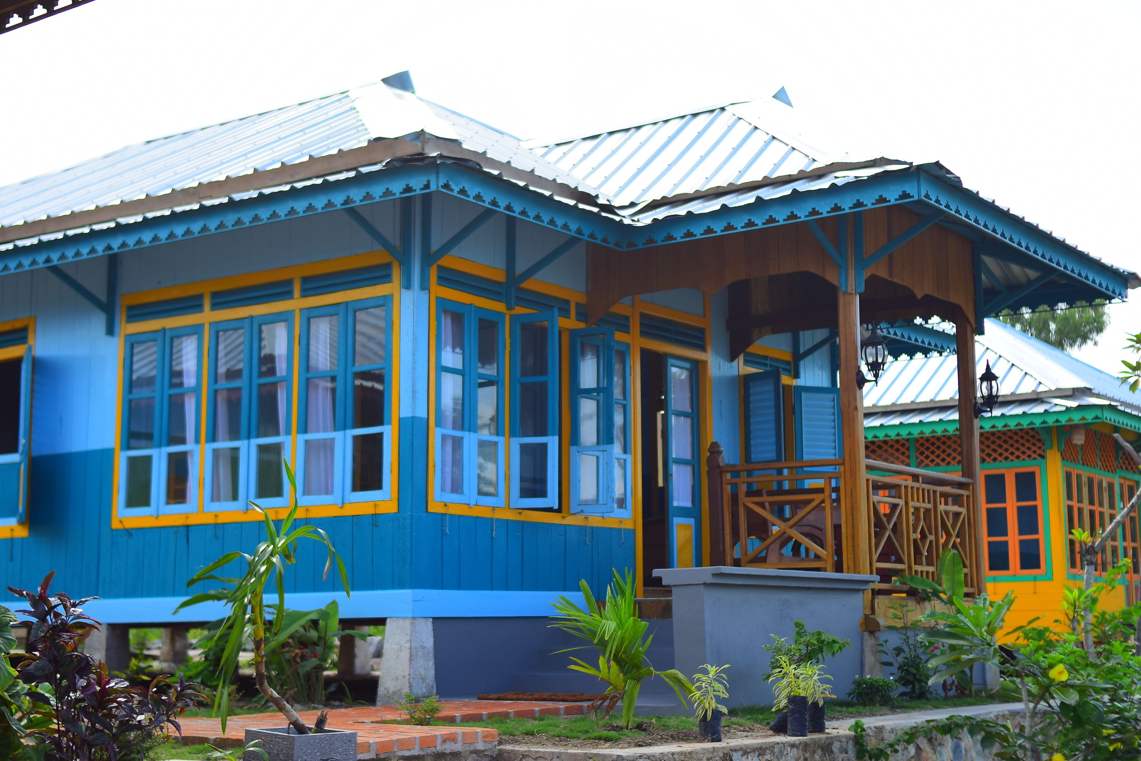 A blue and yellow house with a porch and a covered area.