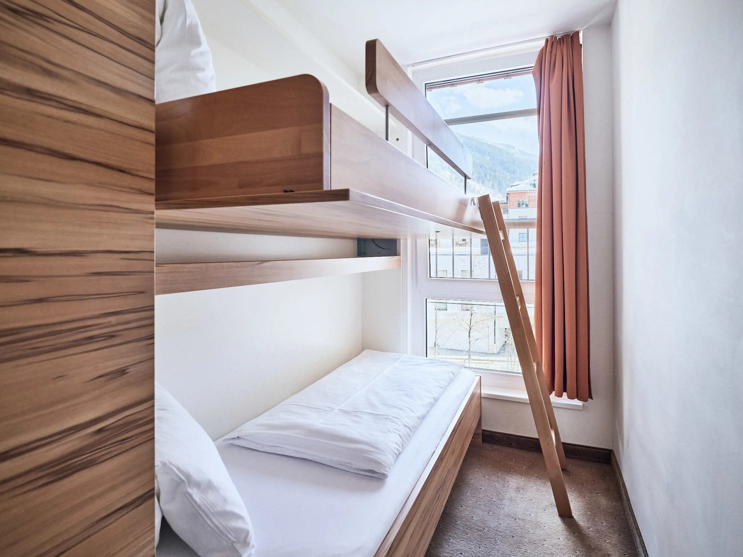 Een slaapkamer met een stapelbed, een raam en gordijnen.