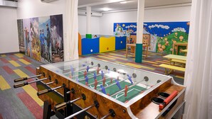 Una habitación con mesa de fútbol, zona de juegos colorida y dibujos de niños en las paredes.