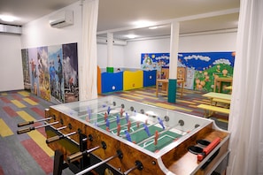 A room with a foosball table, colorful play area, and children's artwork on the walls. - Grafenberg Resort by Alpeffect Hotels (Wagrain)