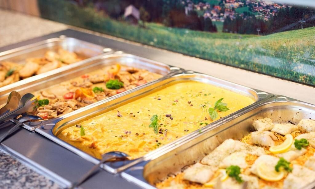 A buffet with various dishes, including a yellow soup, seafood, and a pasta dish.