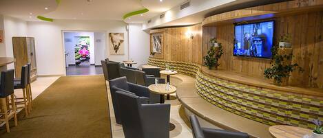 A modern lounge area with seating, a television, and a wooden accent wall.