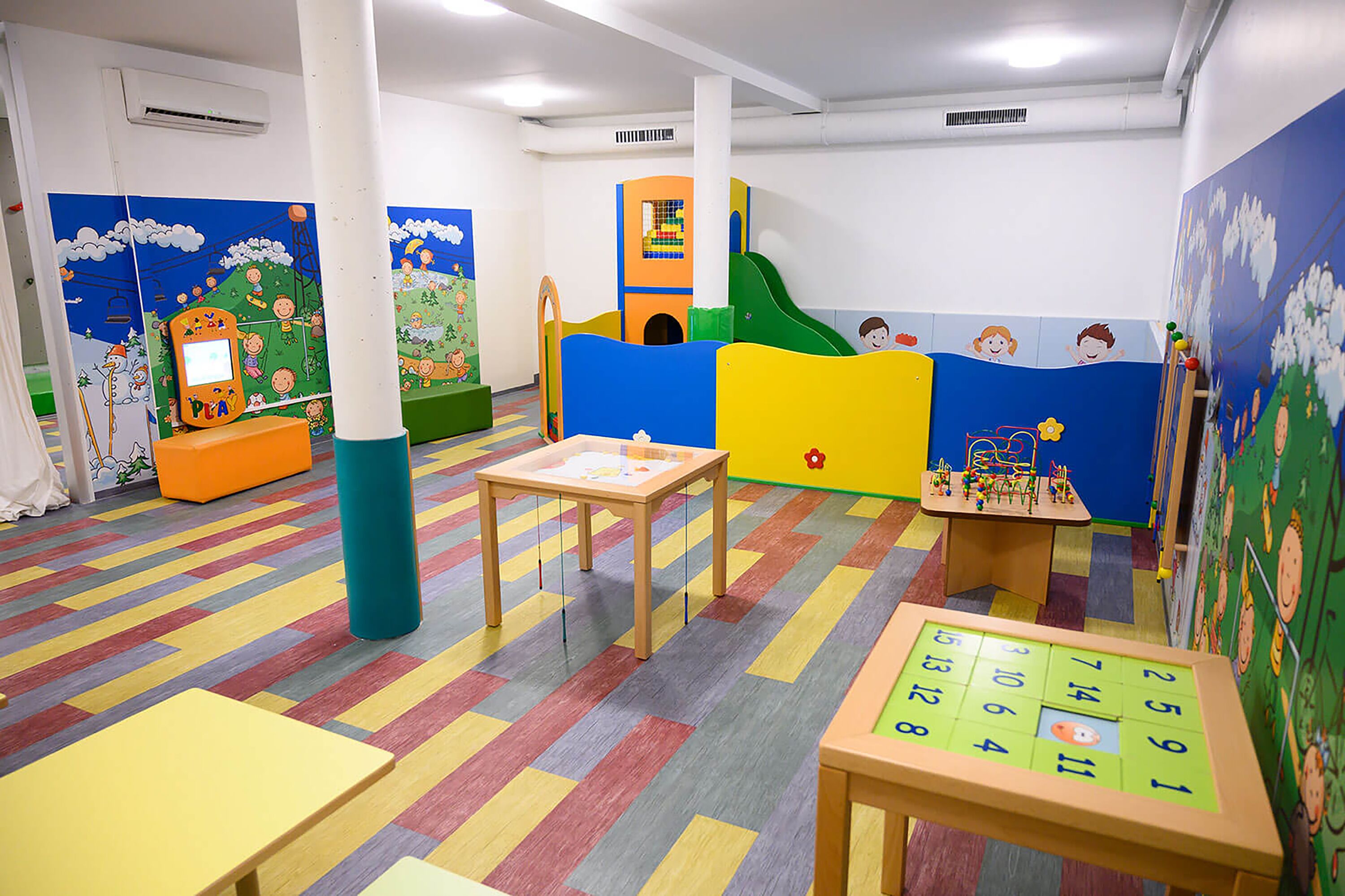 A children's playroom with colorful walls, a play area, and a table with a puzzle.