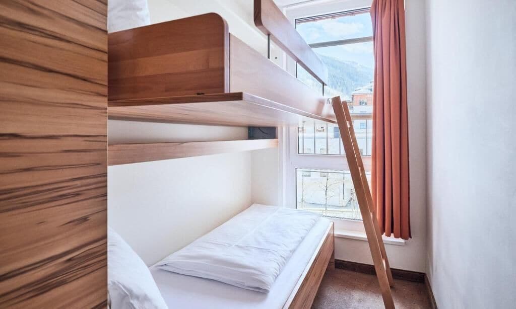 A bunk bed room with a window and curtains.