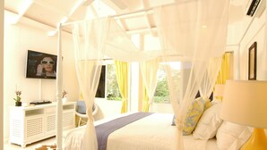 Un dormitorio con cama a dosel, una mesita de noche, una silla, un televisor y vistas al exterior.