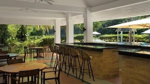 Un restaurante con terraza, columnas blancas y vistas a zonas verdes.