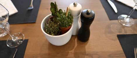 A dining table with a potted plant, a salt and pepper shaker, and a wine glass.
