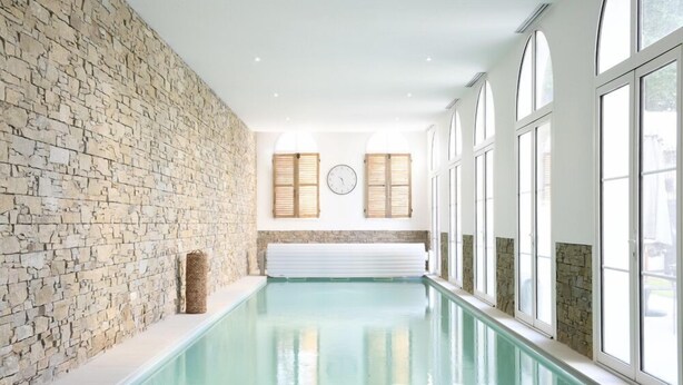 A long indoor swimming pool with stone walls and large windows. - Manoir de l'évêché et Spa (Lisieux)